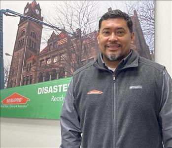 Hispanic male in front of SERVPRO picture with building
